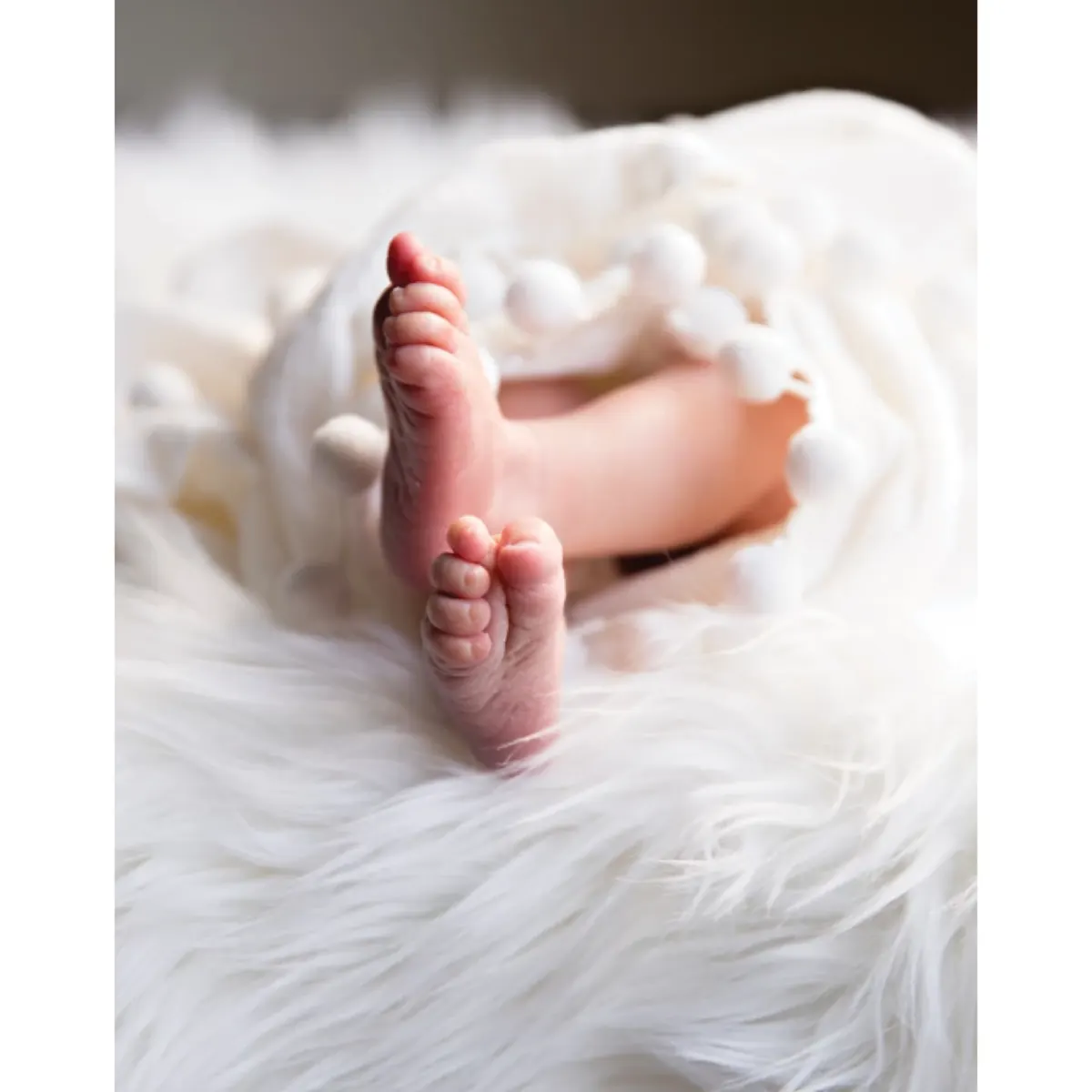 Newborn baby's feet resting on a soft white blanket