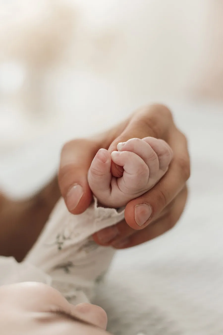 A baby's hand gently holding a parent's finger