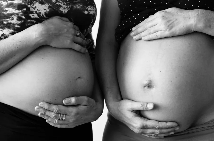 Two expectant mothers cradling their pregnant bellies